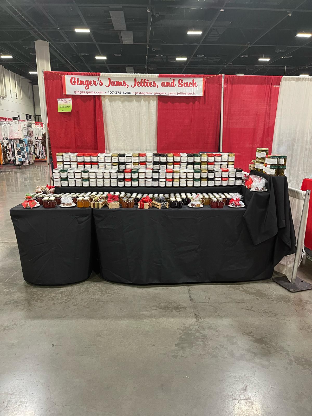 Ginger's Jams full booth at a market — every flavor stacked high with gift favors lined up ready